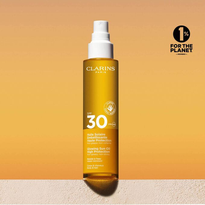 Foto del envase del spray de aceite solar capilar y corporal 30 con un mensaje que anuncia que Clarins se compromete con la protección del medio ambiente